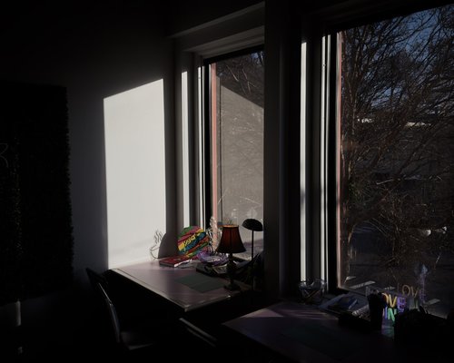 A well lit desk corner next to a window with soft natural daylight
