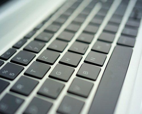 Close up view of hands typing on a modern laptop keyboard with warm ambient light